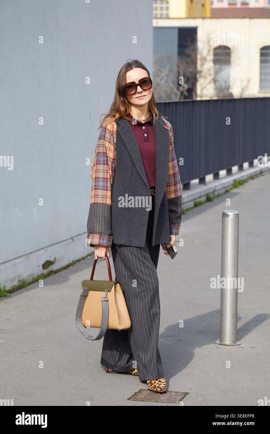 MILANO, ITALIA - 26 FEBBRAIO 2025: Donna con pantalone grigio pinstripe e giacca con maniche a scacchi prima della sfilata di Antonio Marras, Milan Fashi Foto Stock