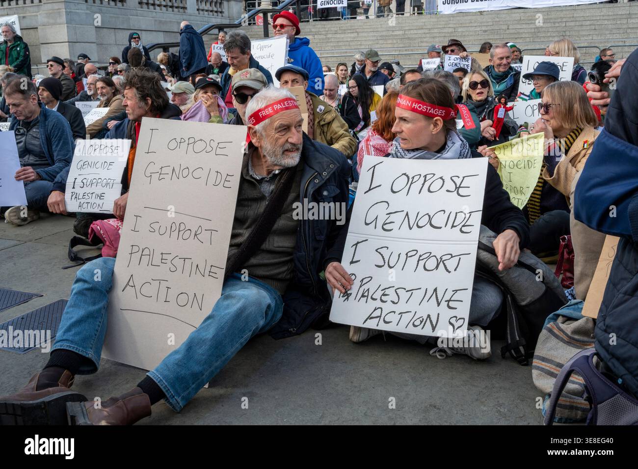 Un manifestante sostiene i segnali "io sono contrario al genocidio, sostengo l'azione palestinese” e attendo di essere arrestato. Foto Stock