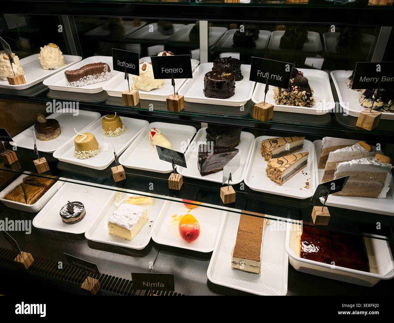 Varietà di torte e dessert esposti in una vetrina del caffè. Concetto di panetteria, scelta, cibo dolce ed esperienza del cliente. Foto Stock
