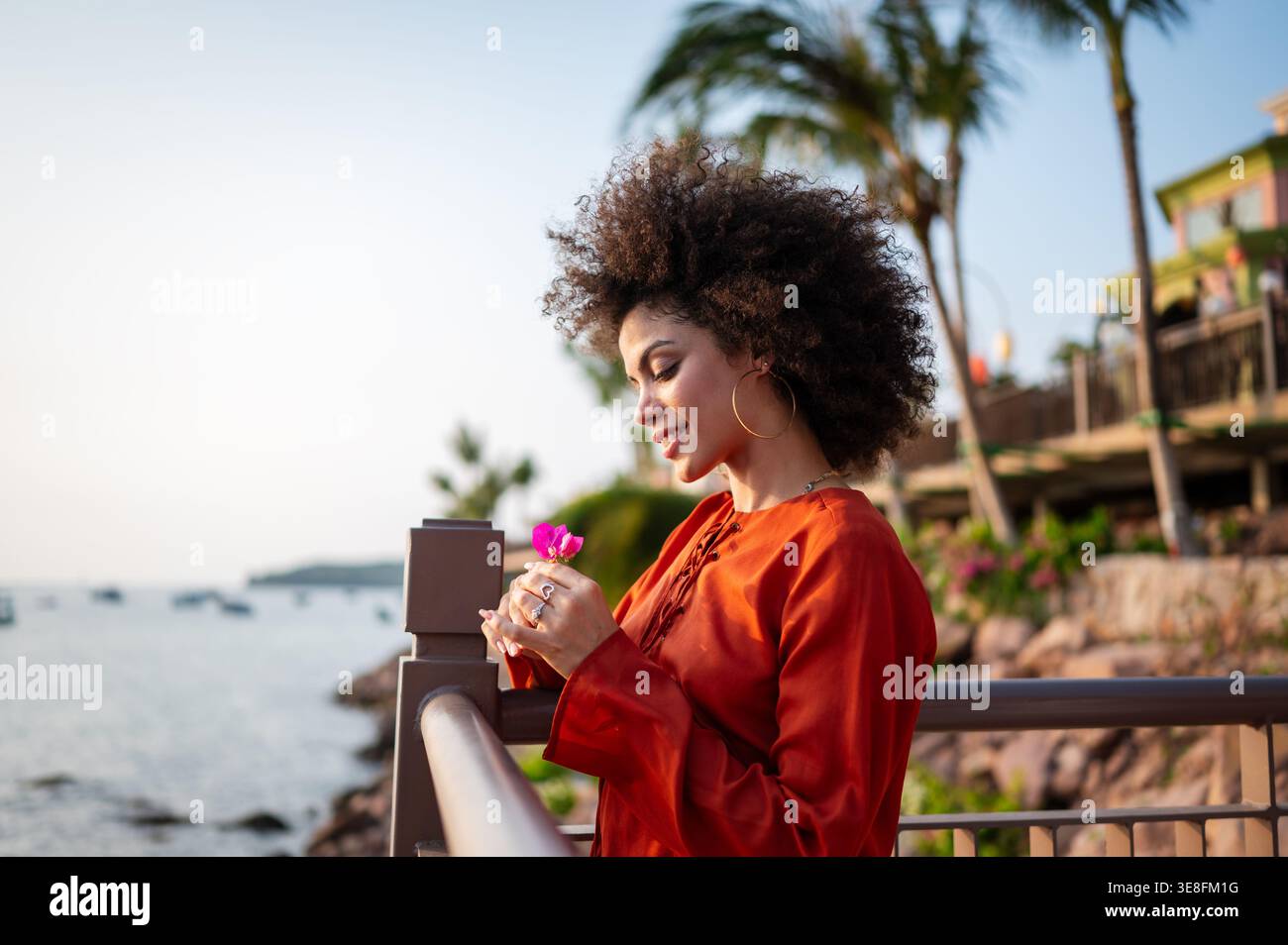 Elegante donna viaggiatrice che si rilassa in una località balneare, godendo della vista panoramica tropicale al crepuscolo Foto Stock