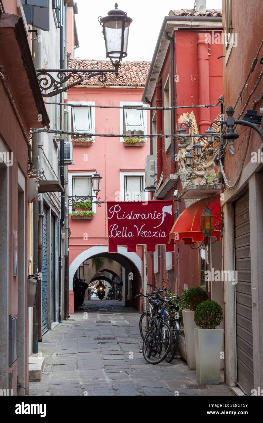 Il ristorante bella Venezia inn è una pittoresca strada laterale a Chioggia, Venezia, Italia, con biciclette di clienti esterni e motociclisti sotto l'arco Foto Stock