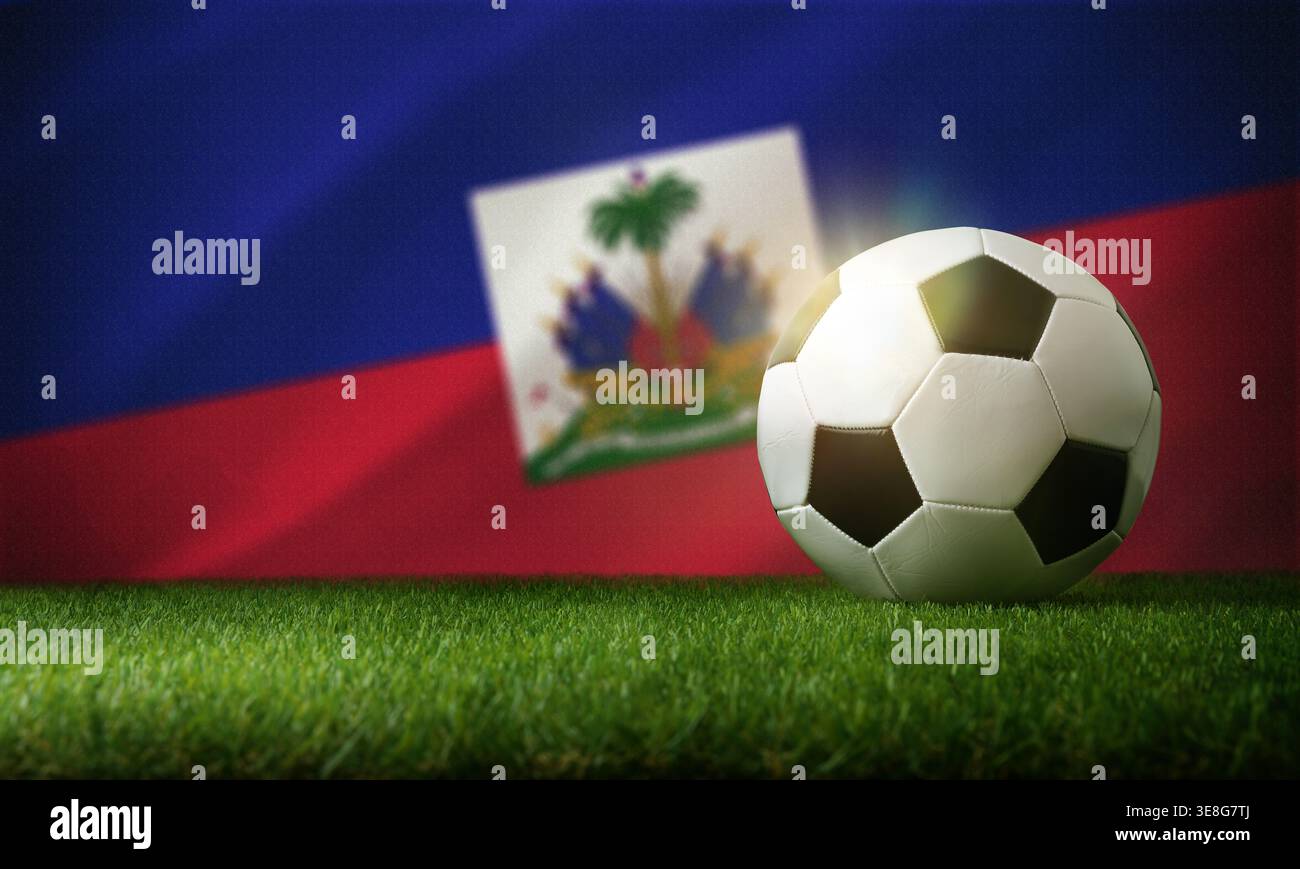 Un pallone da calcio su erba verde con dietro la bandiera sfocata di Haiti, che mette in risalto lo sport, la cultura e il simbolismo nazionale. Foto Stock
