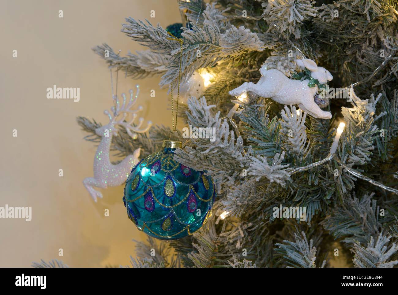 Primo piano di baule natalizie blu con ornamento bianco di renne su rami di alberi smerigliati con luci calde e decorazioni natalizie Foto Stock