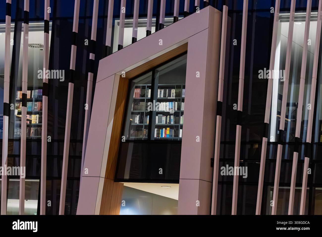 Vinkovci, Croazia - 22 marzo 2026: Un moderno interno della biblioteca visibile attraverso una cornice geometrica della finestra in un edificio urbano contemporaneo che mostra illumi Foto Stock