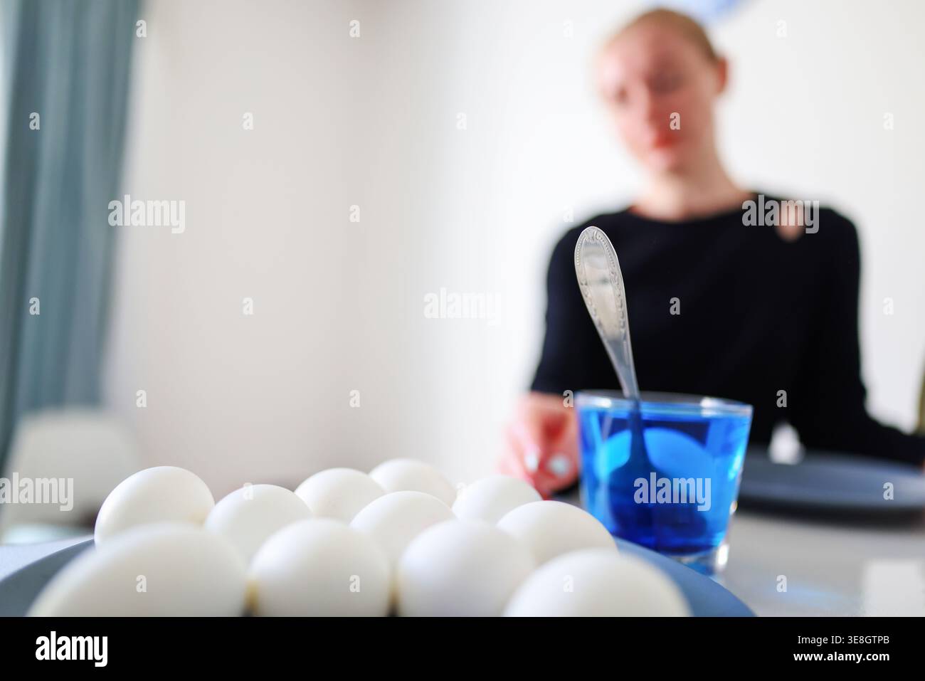 Preparazione per la Pasqua a casa, uova tintorie in liquido blu, semplice scena di vita festiva. Foto Stock