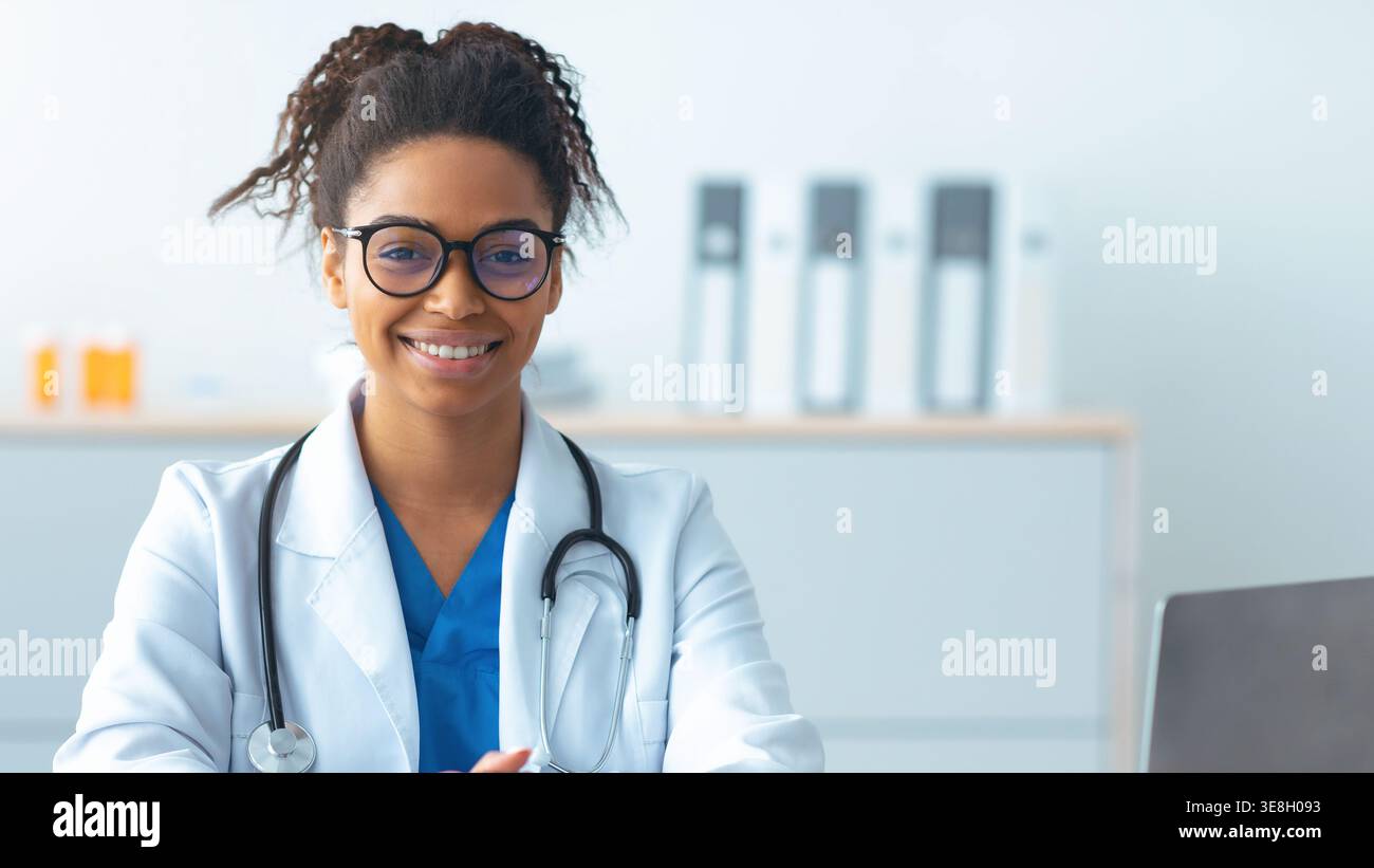 Il medico sorride mentre è seduto nel suo ufficio durante una giornata di lavoro Foto Stock