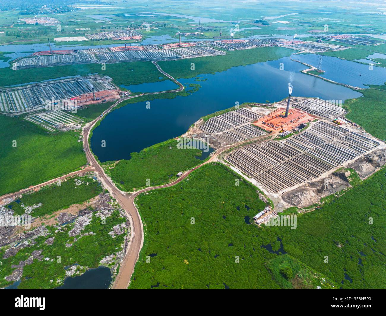 Vista aerea dei forni industriali in mattoni sorgono in un paesaggio verdeggiante, in contrasto con le acque scure degli stagni circostanti, Dacca e Dacca Divisio Foto Stock