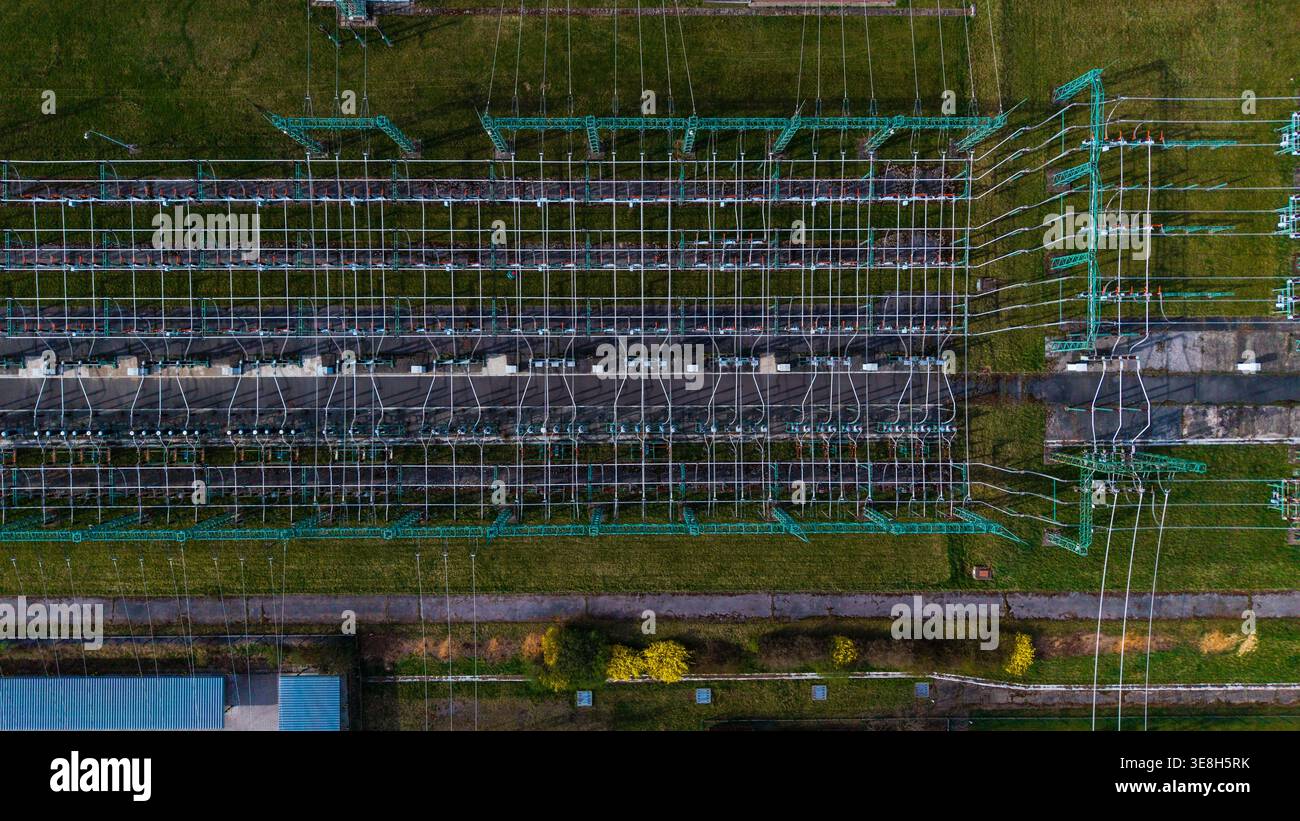 Vista aerea di una centrale elettrica con intricati telai metallici e cavi incrociati tra campi verdi, Praha-Šeberov, Hlavní město Praha, Cechia. Foto Stock