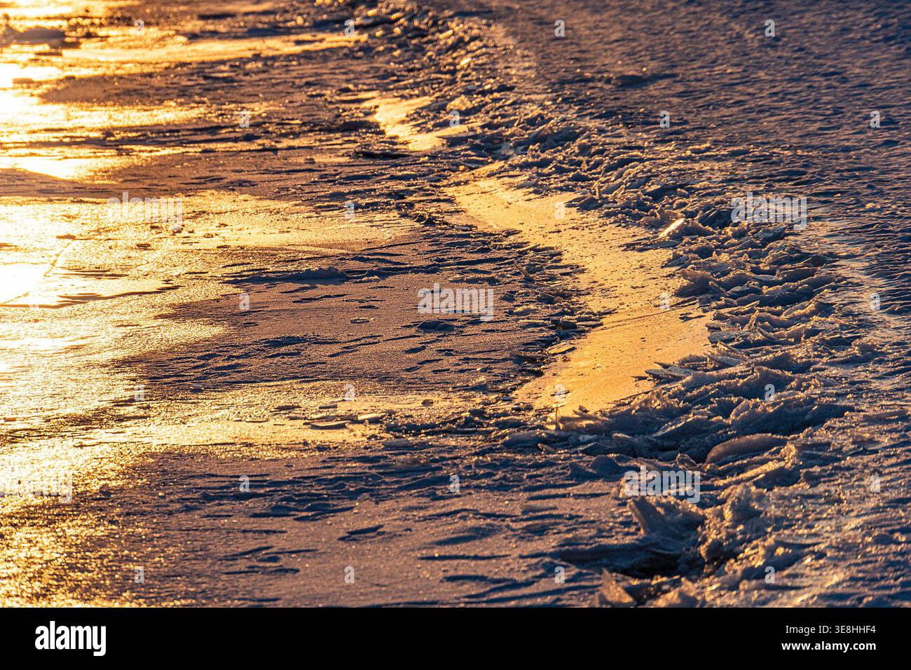 Spiaggia tranquilla, vista ad angolo basso, neve, acqua ghiacciata con macchie di alghe verde scuro, sfondo vetroso, tavolozza di colori sfumati bianco, grigio, verde, blu, rosso, s Foto Stock