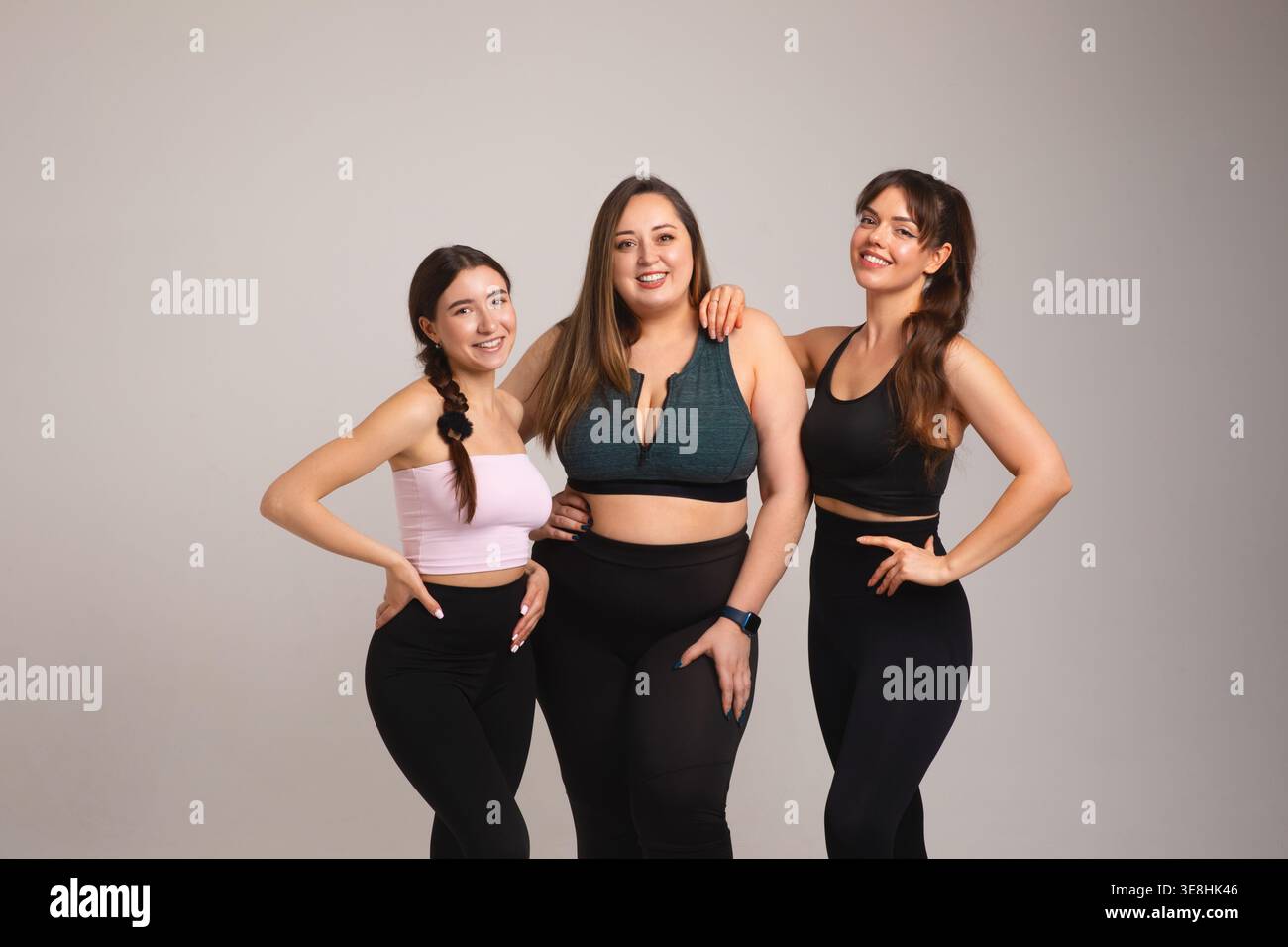 Concetto di bellezza inclusivo. Un gruppo di fitness femminile molto diversificato, tra cui una donna ricurva, si distingue con sicurezza per gli abbigliamento da studio. Modelli femminili Foto Stock