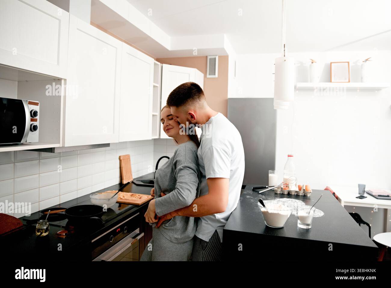 Giovane coppia che abbraccia mentre cucina a casa. Concetto di amore, stile di vita e relazione. Foto Stock