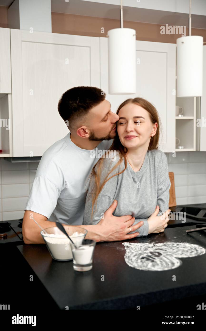 Una giovane coppia che prepara il cibo e si abbraccia a vicenda. Concetto di amore e stile di vita. Foto Stock