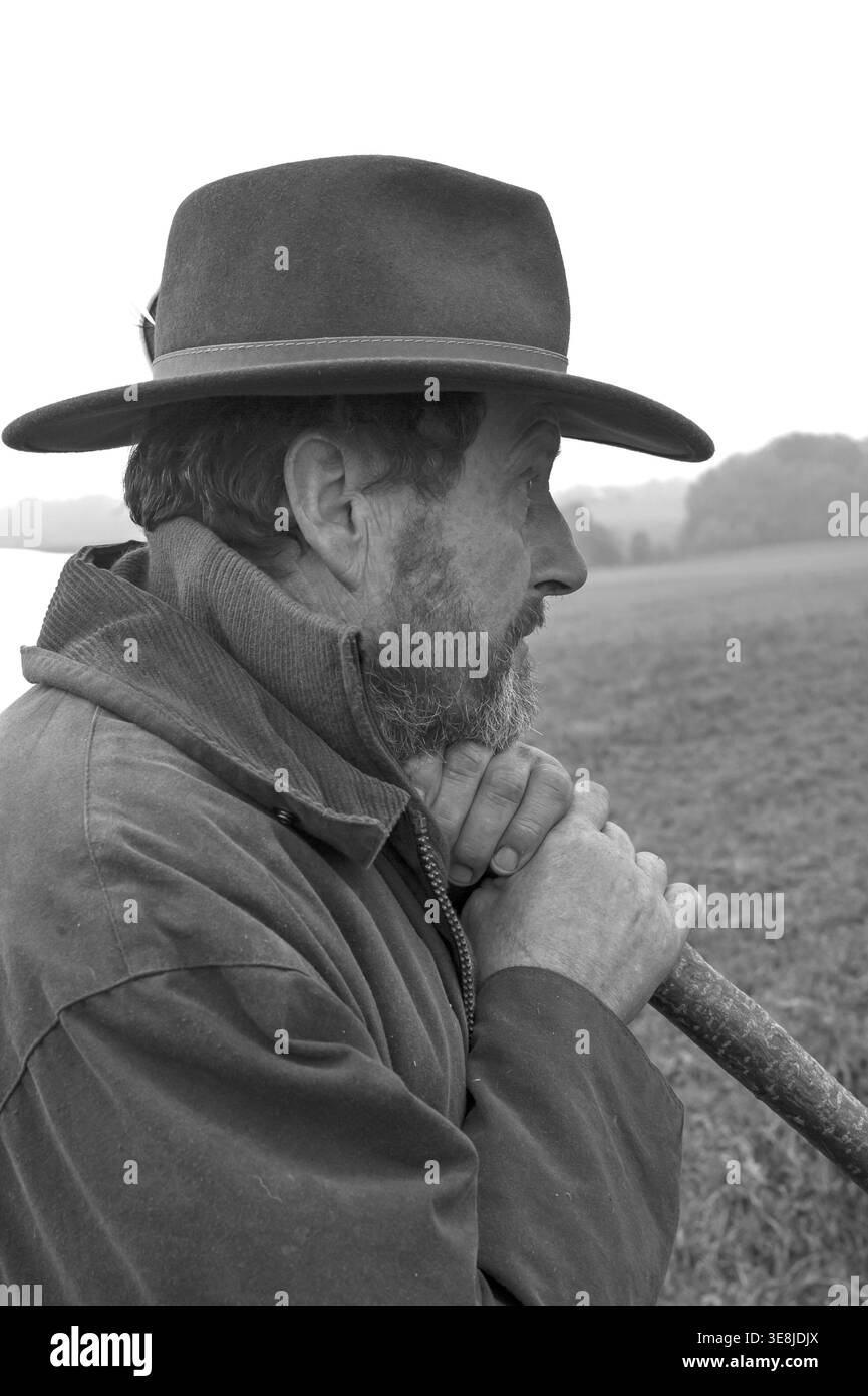 Ritratto di un contadino che indossa un cappello, appoggiato su un bastone mentre mangia il suo bestiame, bianco e nero, Media Franconia, Baviera, Germania Foto Stock