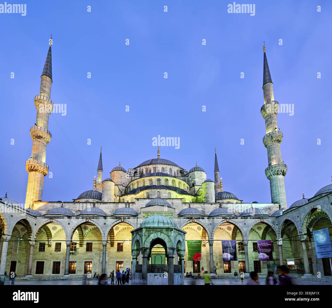 La gente cammina intorno alla Moschea Blu di Istanbul mentre il sole tramonta, illuminando i suoi minareti e l'architettura Foto Stock