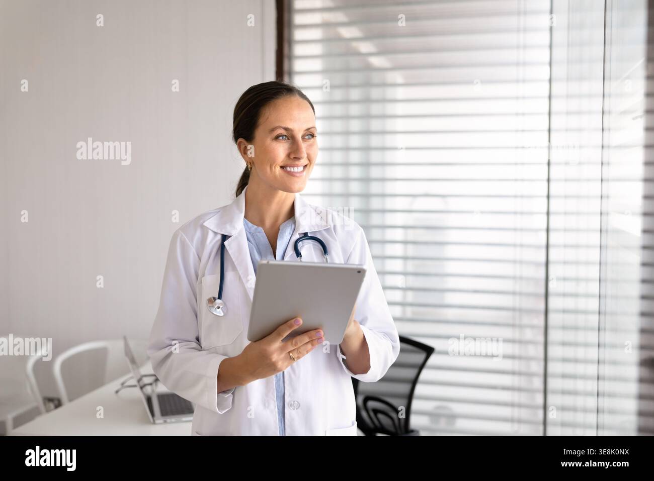 Medico donna in possesso di tablet digitale in piedi nello studio medico Foto Stock