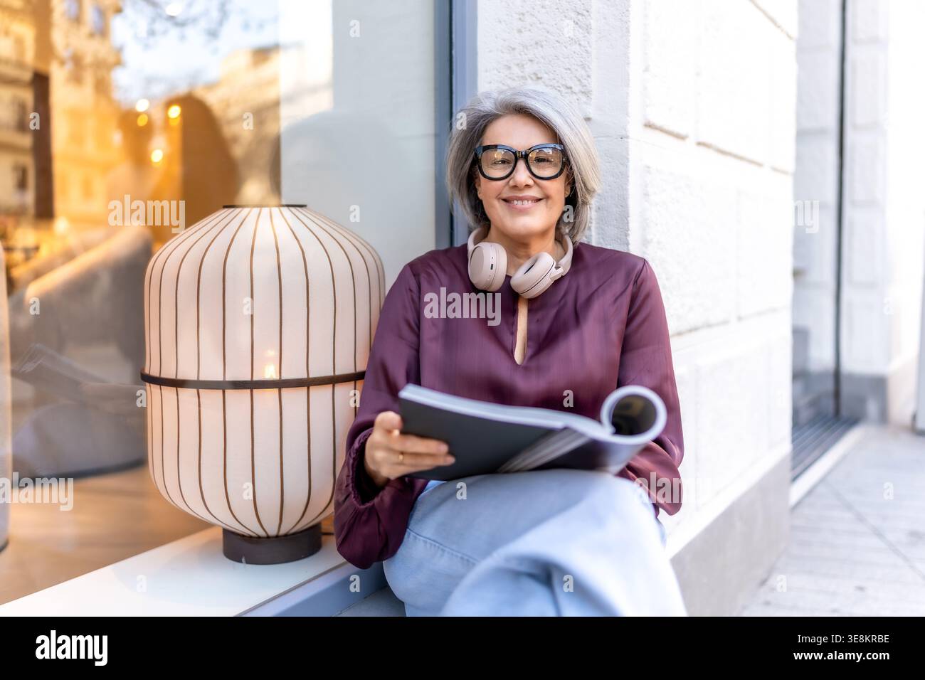 Donna matura sorridente rilassante leggendo libri strada Foto Stock