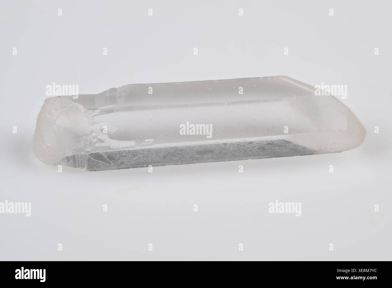 Punta in cristallo di roccia lucida fotografata su sfondo bianco, punta con estremità liscia con facce lucide, nuvole interne e microbolle, calda Foto Stock