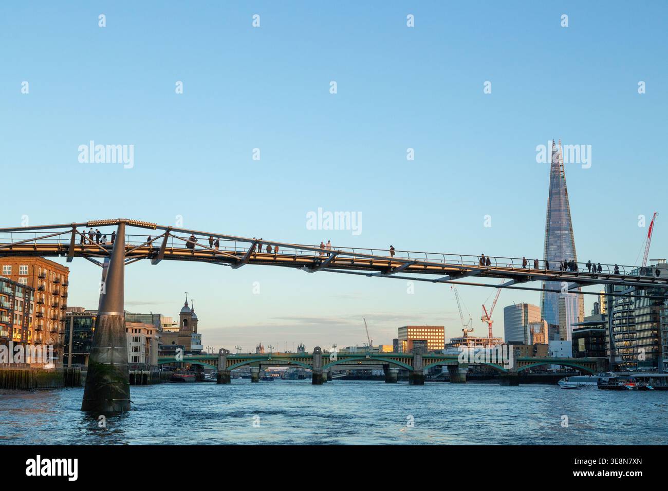 Il Millennium Bridge al tramonto sul Tamigi a Londra con il grattacielo Shard sullo sfondo Foto Stock