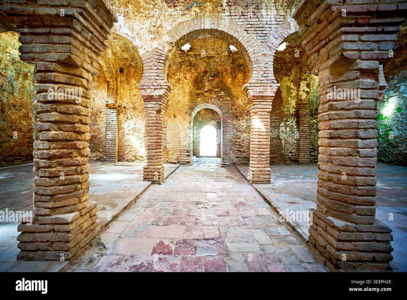 I visitatori camminano attraverso le storiche terme arabe di Ronda. La struttura presenta archi in pietra e luce naturale che illuminano lo spazio. Foto Stock