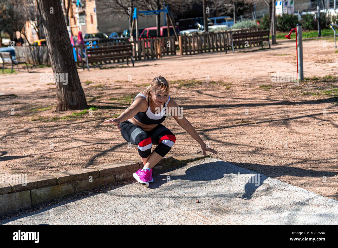 Donna anziana che fa esercizio all'aperto facendo squat nel parco Foto Stock