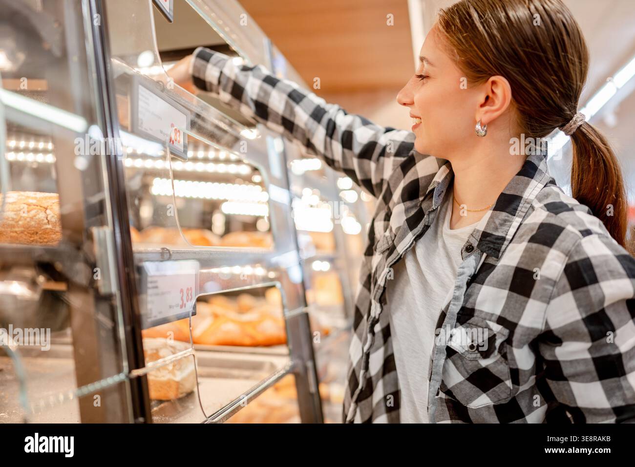 Ragazza che sceglie il pane nel reparto di panetteria del supermercato Foto Stock