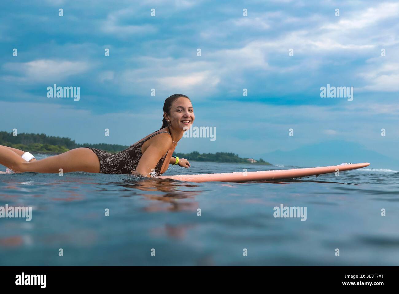 Giovane donna che trasmette in tavola da surf Near Shore, Lifestyle Capture con Bright Mood, Coastal Sky e coinvolgente Foto Stock