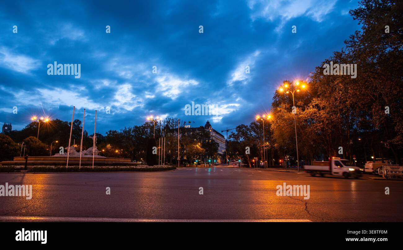 Al crepuscolo, l'Hotel Ritz e il Fuente de Neptuno di Madrid sono illuminati da caldi lampioni, adagiati su un suggestivo e dolente cielo blu Foto Stock