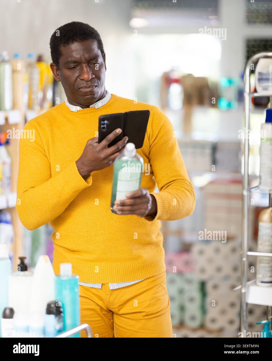 L'acquirente maschile controlla un codice QR su un'etichetta di spugna per lavastoviglie nel supermercato Foto Stock