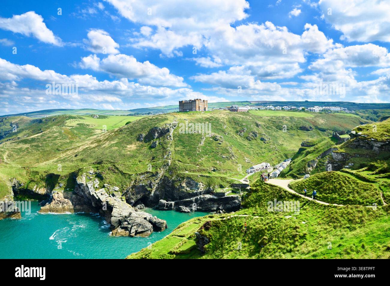 Costa frastagliata della Cornovaglia presso il sito storico del castello di Tintagel, con il Camelot Castle Hotel in cima a una scogliera in una giornata di sole a fine estate, in Cornovaglia, Regno Unito Foto Stock