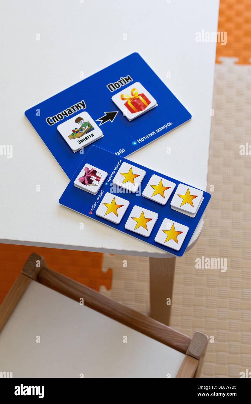 Le carte di ricompensa del comportamento in ucraino riposano su un tavolo bianco. Le tavole blu mostrano stelle e un simbolo presente per motivare. Uno strumento di pianificazione visiva Foto Stock