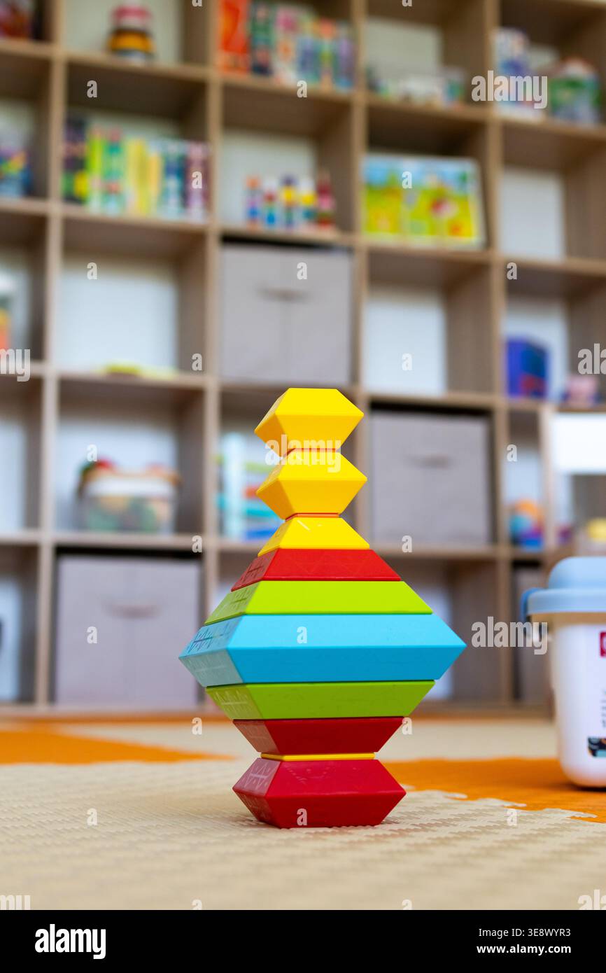 I blocchi esagonali colorati sono impilati in una torre simmetrica su un tappetino in schiuma con vani portaoggetti con messa a fuoco morbida. Un'attività di costruzione giocosa Foto Stock