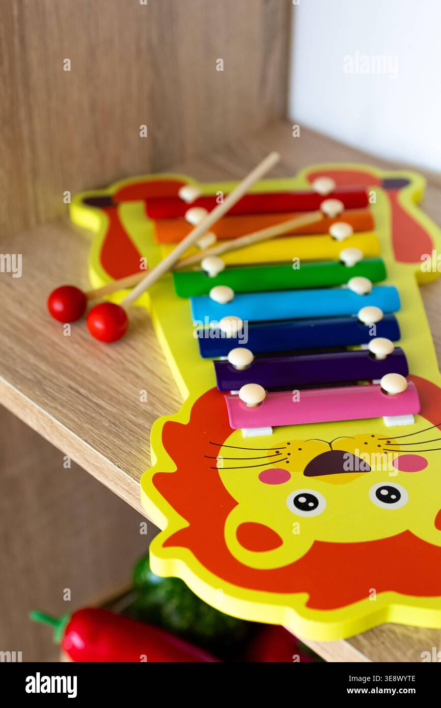 Giocattolo con xilofono arcobaleno a forma di leone allegro su un ripiano di legno. Due mazzuoli si trovano lungo i bar, invitando i bambini curiosi a toccare le canzoni più semplici Foto Stock