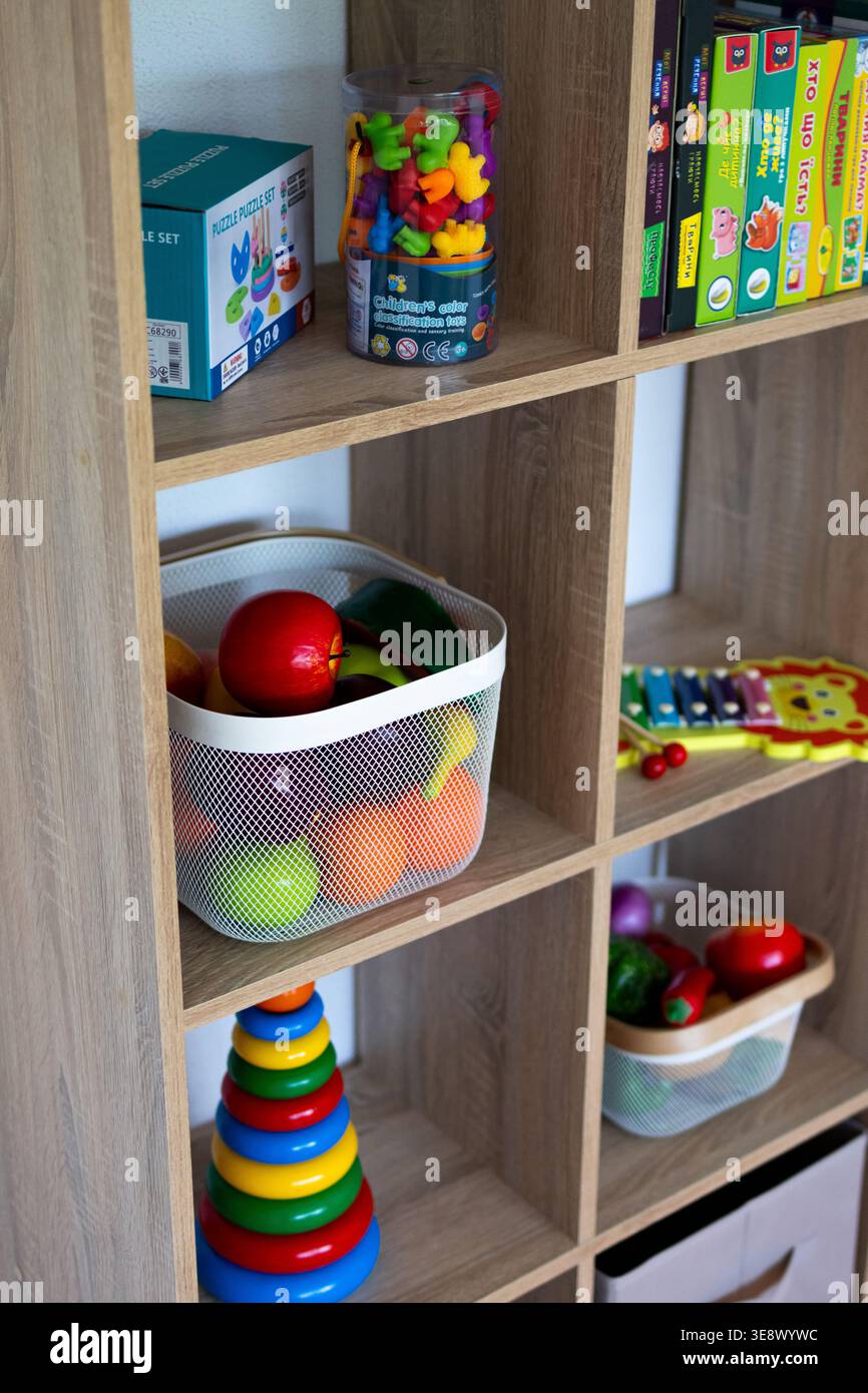 Vista verticale dei ripiani cubici in legno con la finta produzione di una torre ad anello impilabile e uno xilofono leone. I coloratissimi giocattoli didattici sono ben conservati Foto Stock