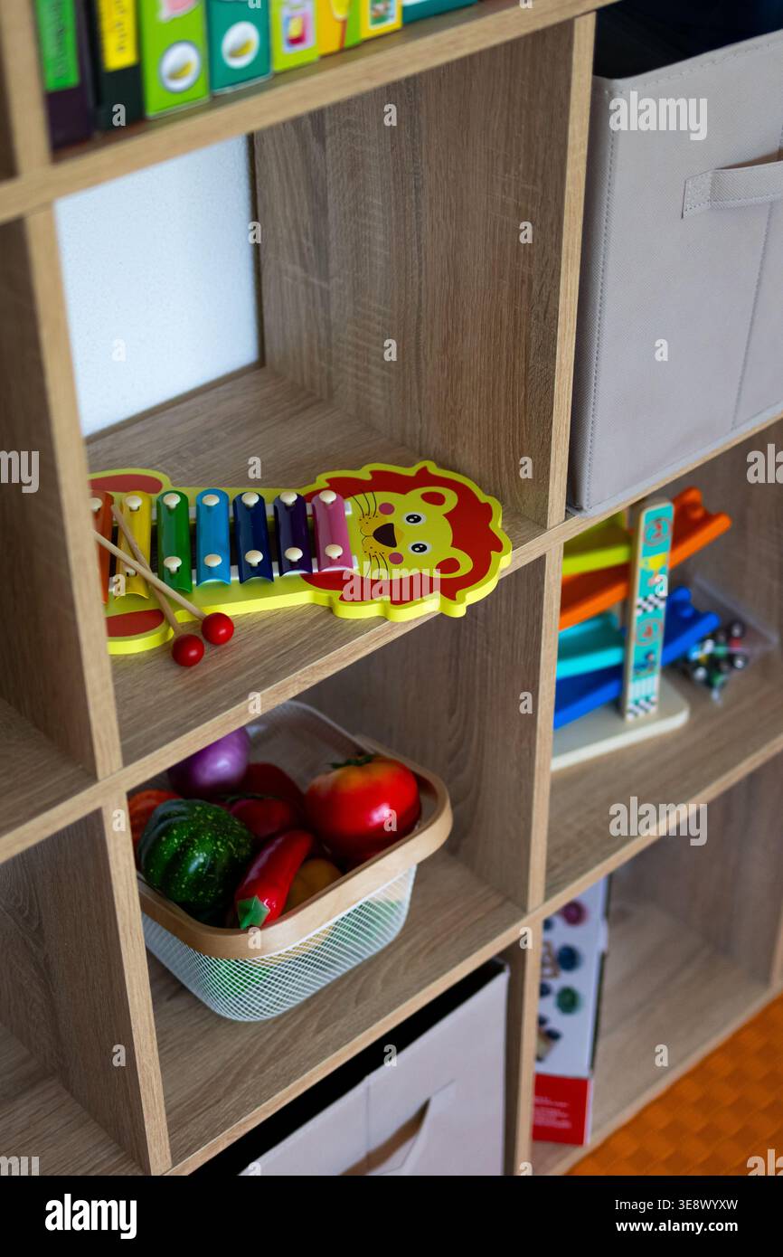 I vani portaoggetti dei giocattoli mostrano uno xilofono di leone sopra un cestino di verdure finte con un giocattolo in legno a rampa nelle vicinanze. Foto Stock