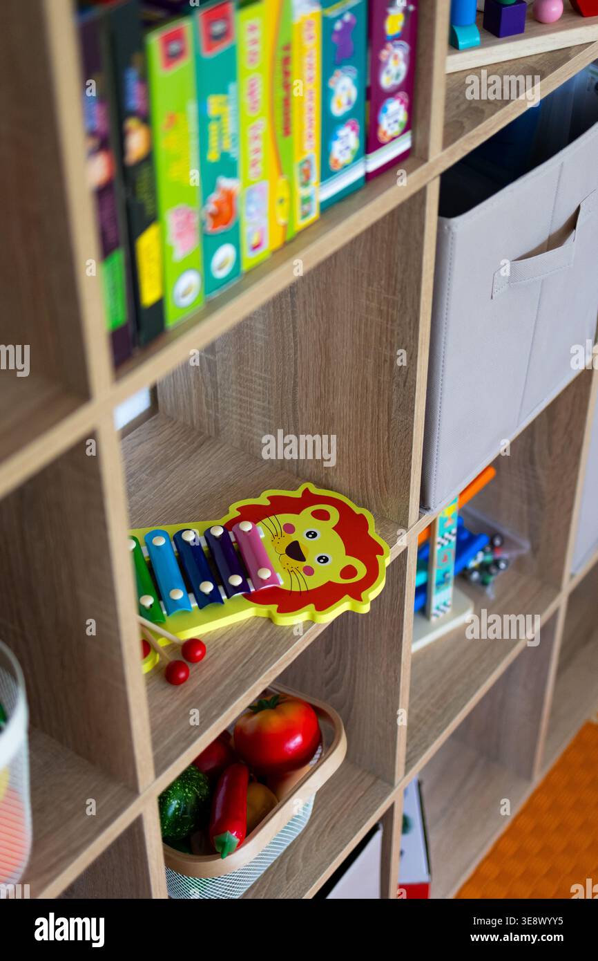 La vista angolata su uno scaffale dei giocattoli rivela un allegro xilofono leone e cesti di prodotti finti con pile di puzzle sopra. Foto Stock
