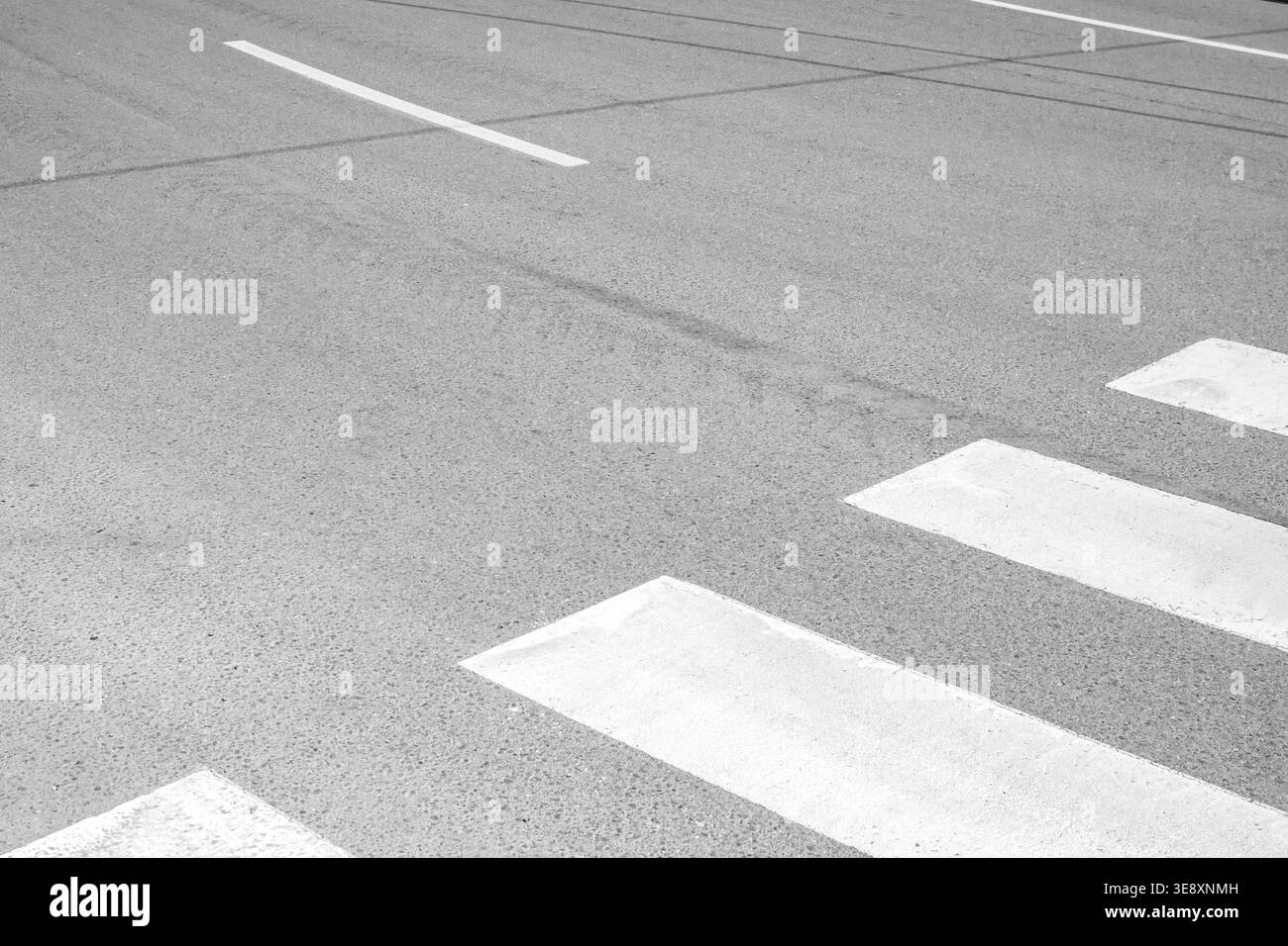 Strisce bianche di attraversamento pedonale su strada asfaltata con composizione urbana pulita e spazio di copia minimo. Foto Stock