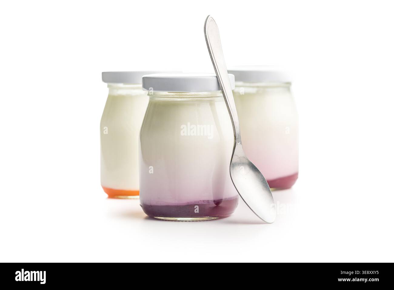 Cremosi vasetti di vetro di yogurt alla frutta con fondo a strati di bacca e pesca, disposti con un cucchiaio per una colazione o uno spuntino fresco e salutare; luminosi, minimali Foto Stock