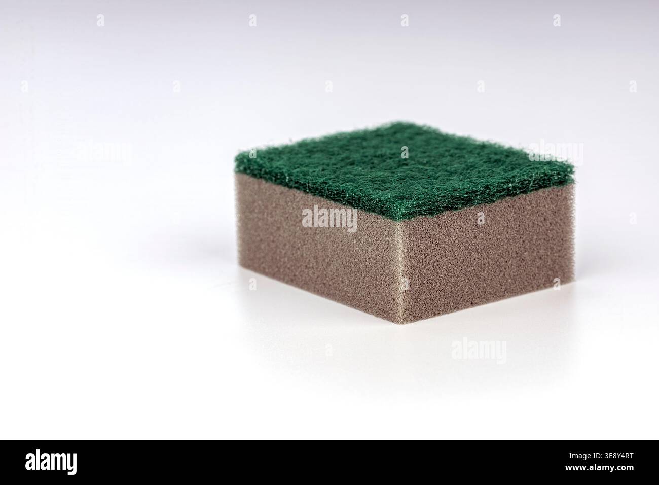 Spugna da cucina di qualità professionale che combina un tampone di pulizia verde testurizzato sulla parte superiore con una base morbida e assorbente in schiuma abbronzante, perfetta per le pulizie domestiche Foto Stock