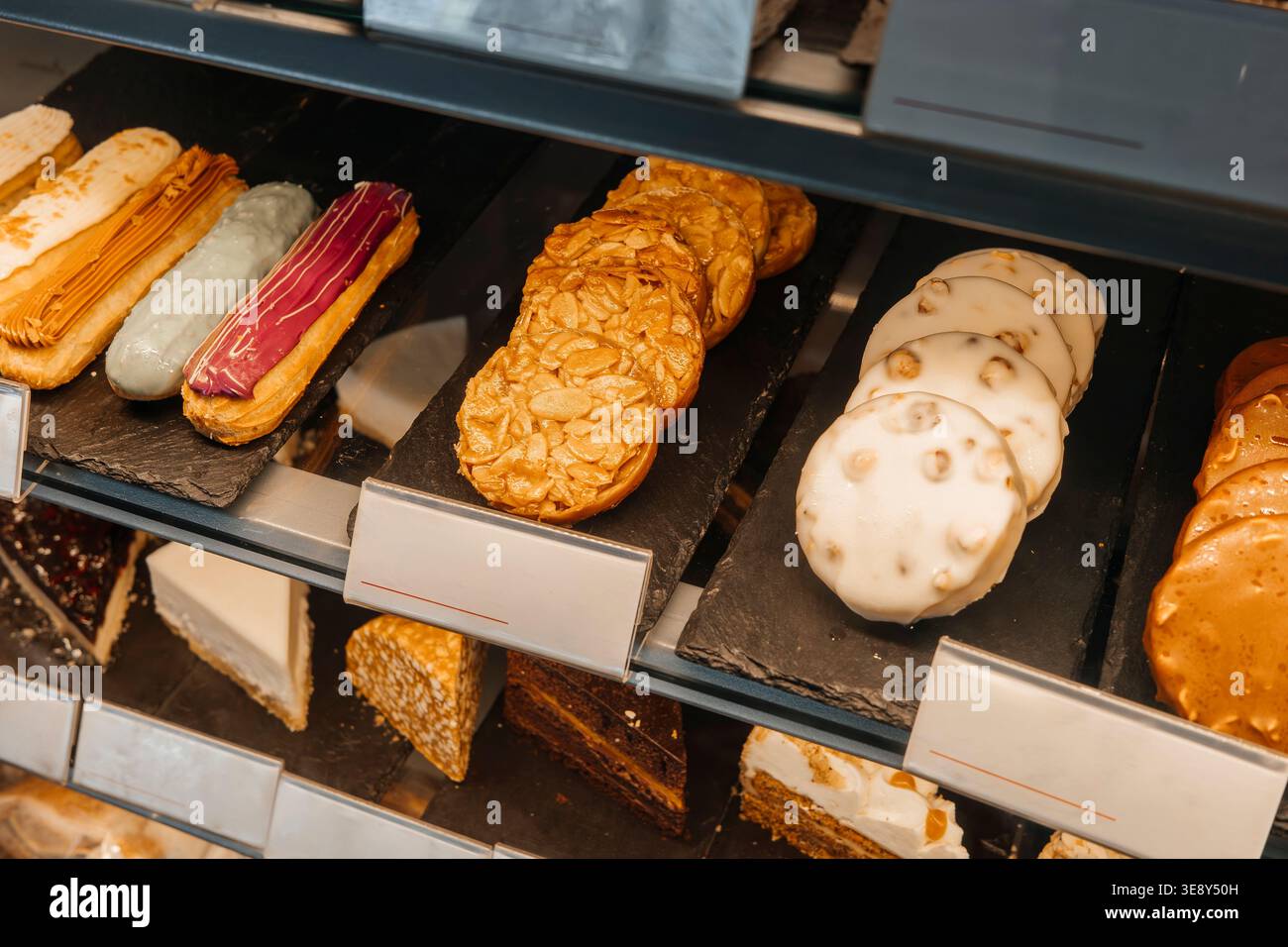 Pasticceria mista e biscotti in vetrina, dessert assortiti su vassoi all'interno del negozio. Concetto: Assortimento di dolci da forno Foto Stock