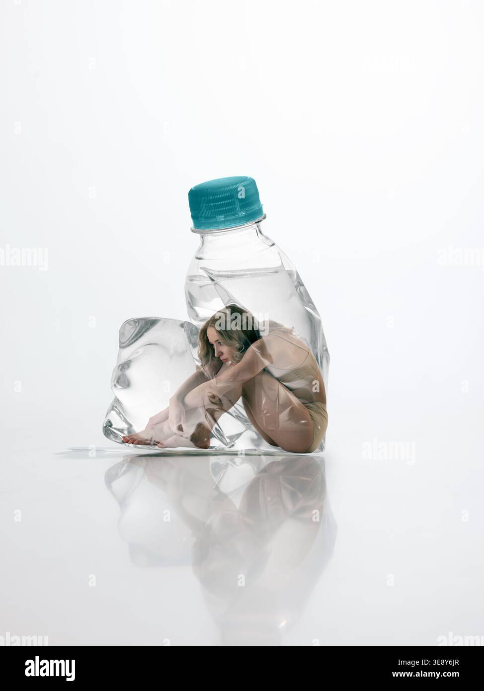 Donna seduta all'interno di una bottiglia di plastica deformata che mostra stanchezza ed esaurimento emotivo Foto Stock