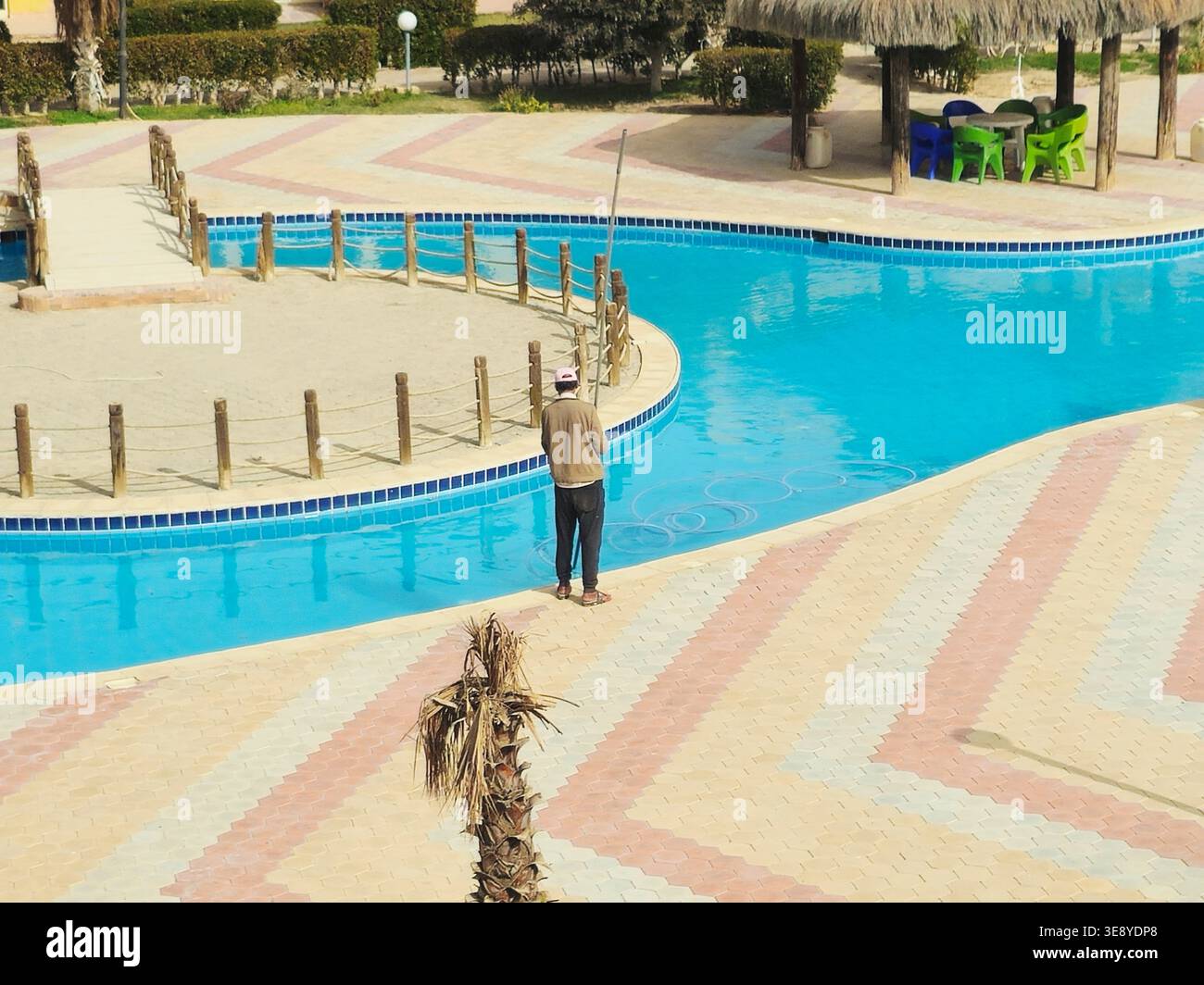 Sinai del Sud, Egitto, gennaio 31 2026: Manutenzione della piscina in corso, una persona che utilizza un maglione di rete attaccato a un palo per pulire la superficie di Th Foto Stock
