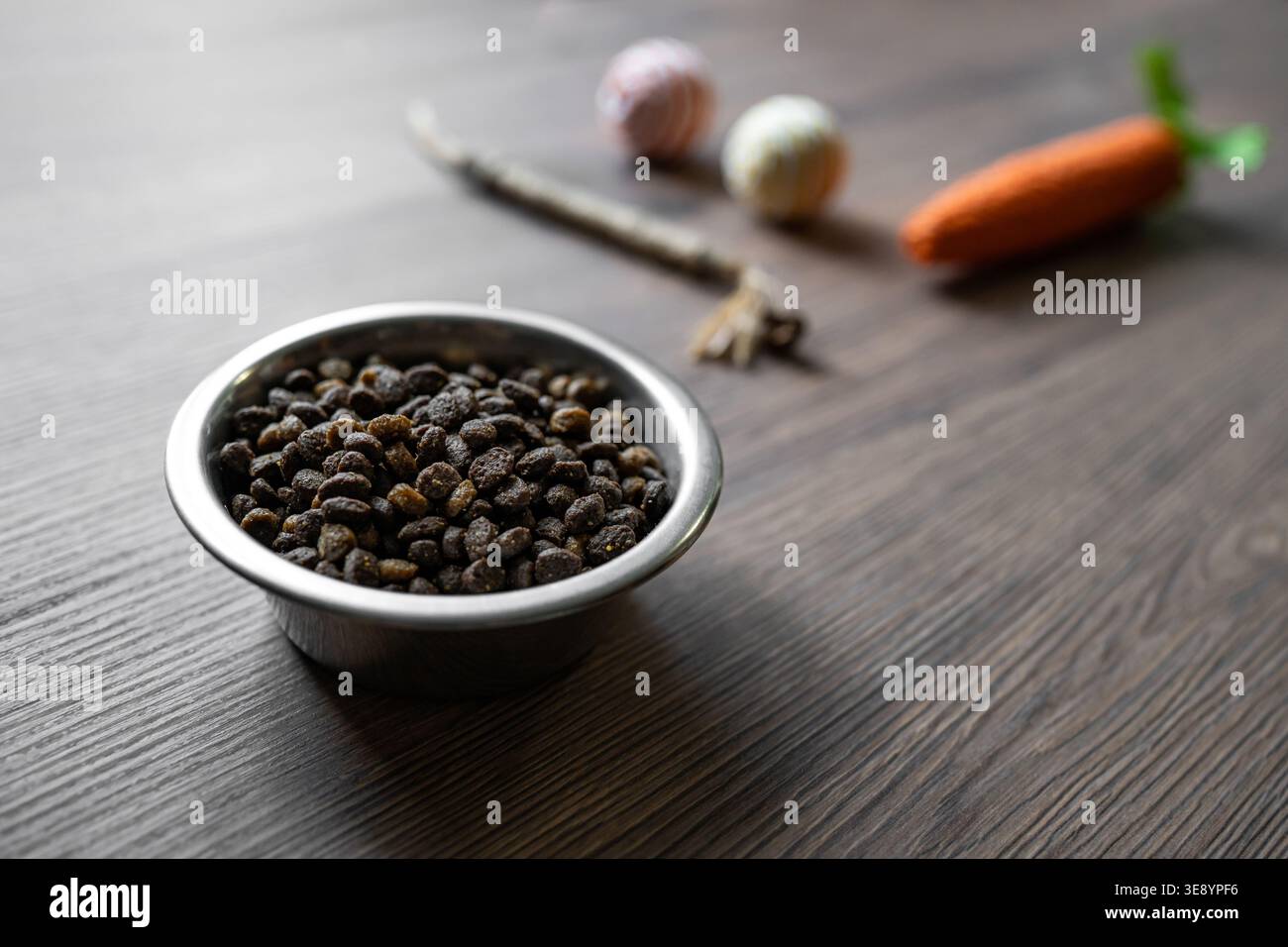 Alimenti secchi Cat in ciotola con giocattoli sfocati sullo sfondo, cura degli animali domestici e concetto di stile di vita, attenzione selettiva con spazio di copia per la pubblicità Foto Stock