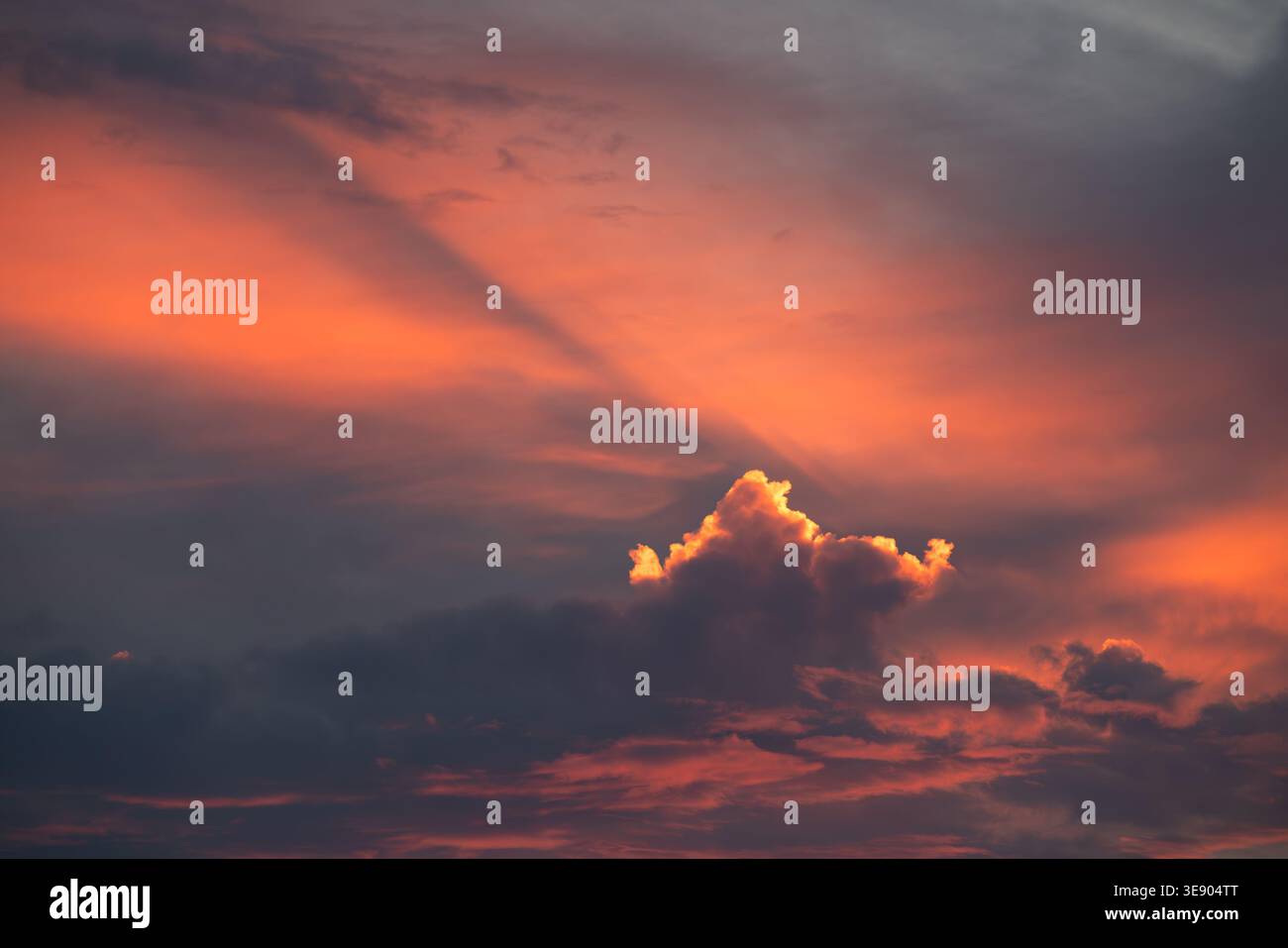 Una singola nuvola è illuminata da una splendida luce calda e colorata del tramonto Foto Stock