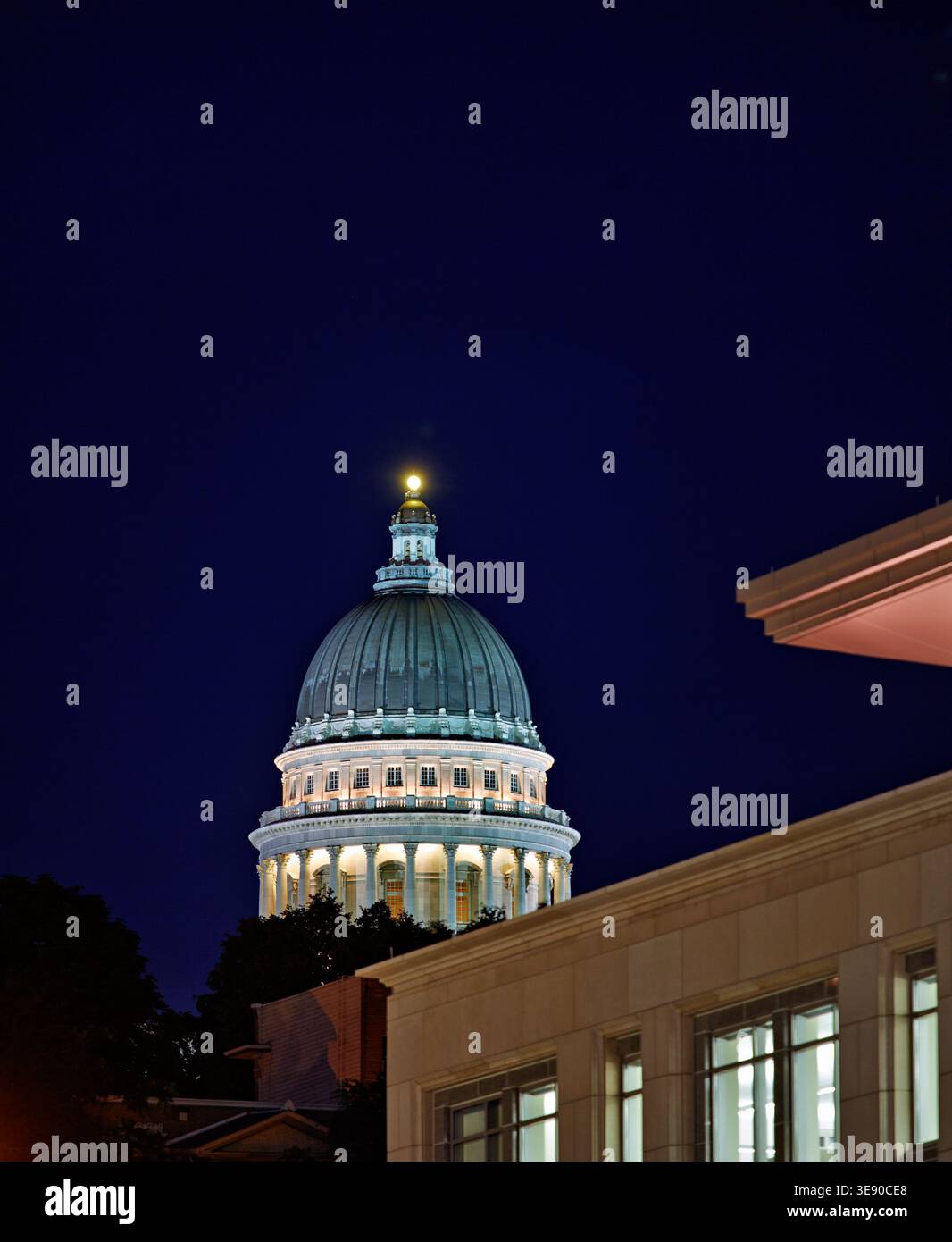 La cupola del Campidoglio dello Utah si erge luminosa di notte a Salt Lake City. Gli edifici circostanti sono bui sotto il cielo notturno. Foto Stock