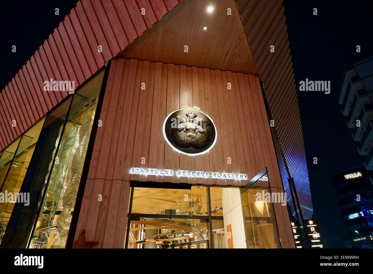 Starbucks Reserve Roastery esterno di notte con logo illuminato e moderna facciata in legno Foto Stock