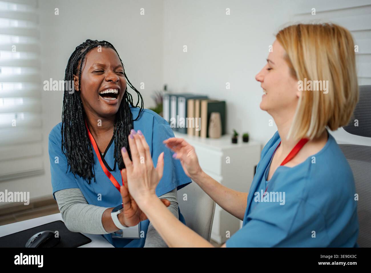 Professionisti medici felici ridendo e dando cinque alto in clinica Foto Stock