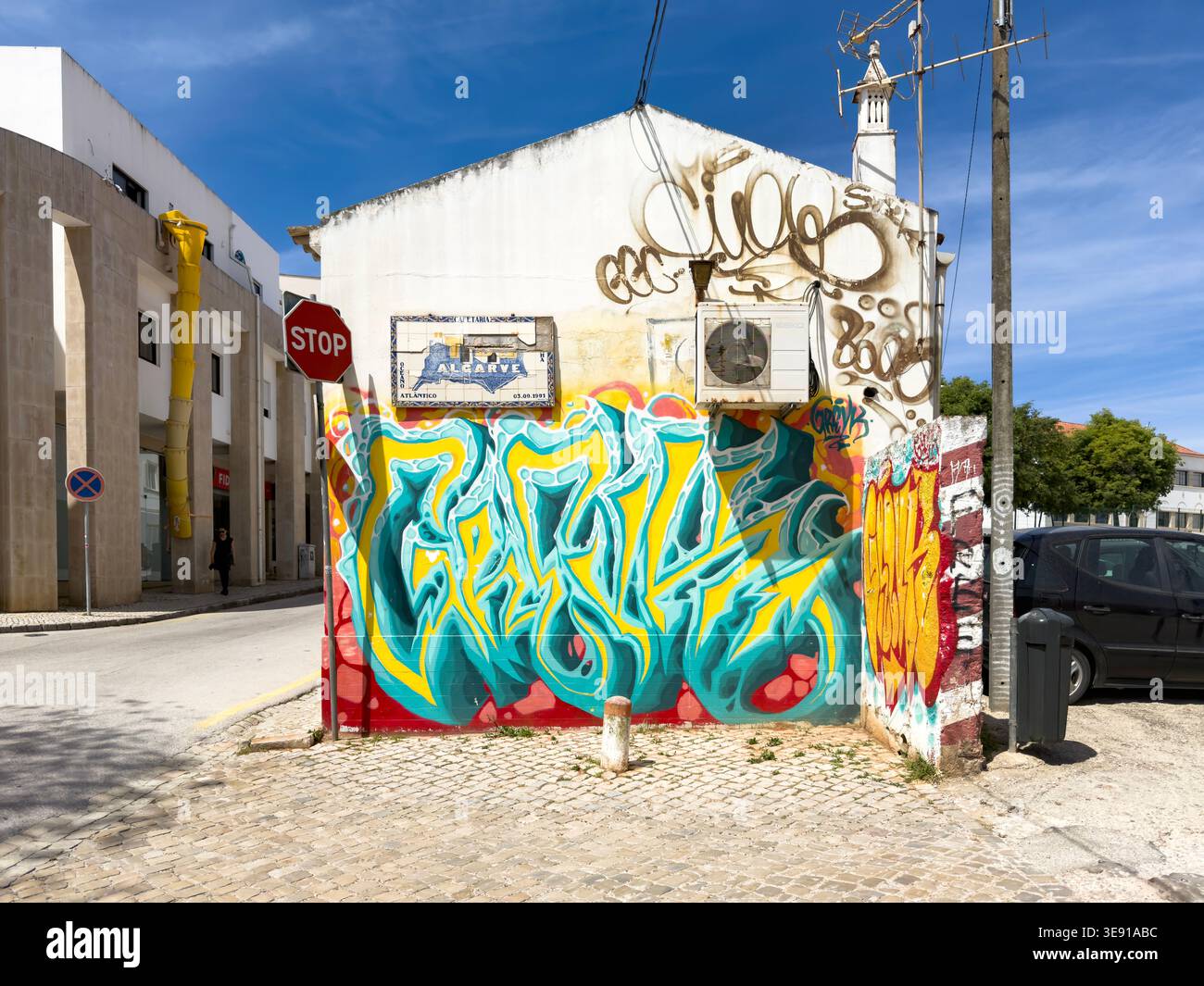 Colorato murale di graffiti su un muro bianco dell'edificio con aria condizionata e un cartello dell'Algarve a Lagos in Portogallo Foto Stock