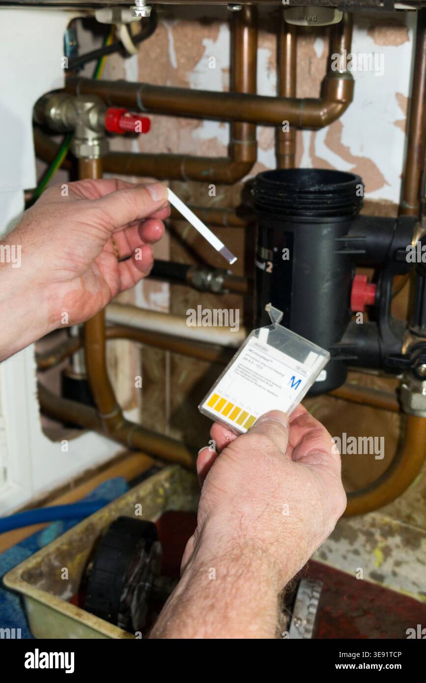 Ingeniero del gas che testa l'alcalinità e l'acidità del pH durante la manutenzione annuale di una caldaia combinata e il test di sicurezza del gas per un locatore in una proprietà in affitto. Tecnico Gas Safe / Which? Trusted Trader. (148) Foto Stock