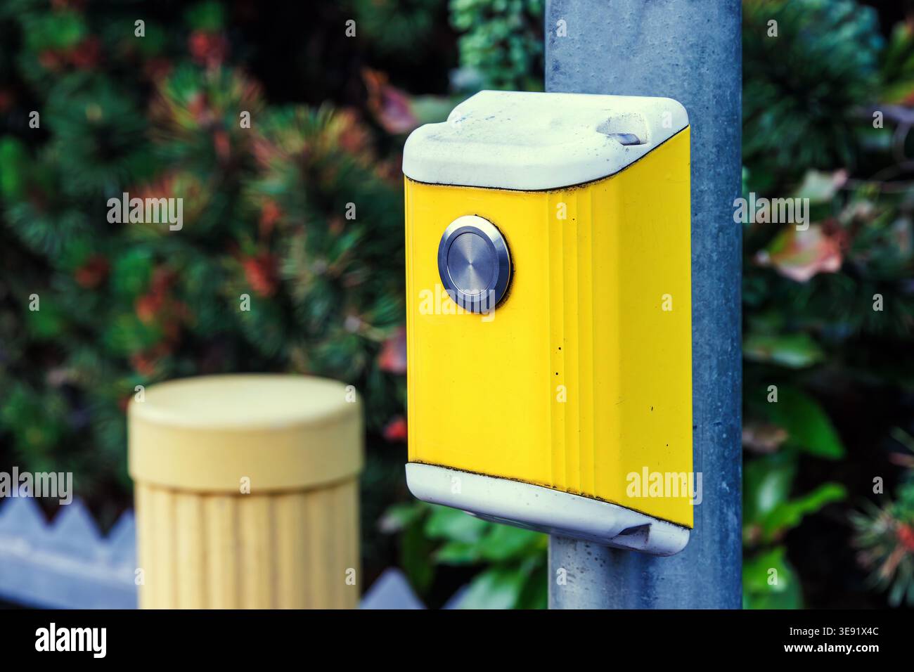 Primo piano di un pulsante giallo di attraversamento pedoni montato su un palo. Infrastrutture stradali urbane Foto Stock