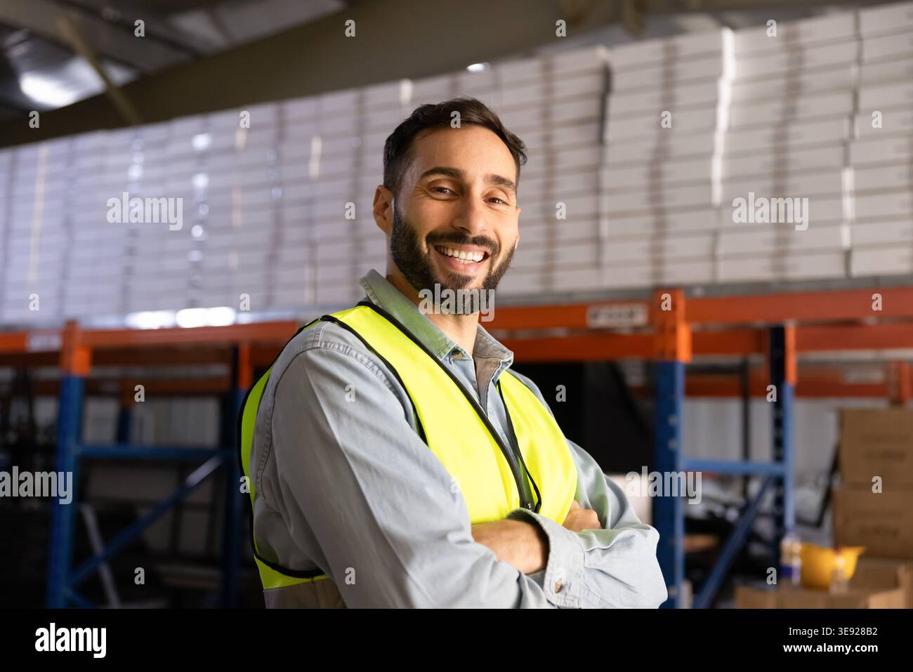 Ritratto di un lavoratore professionista sorridente si trova in un magazzino industriale Foto Stock